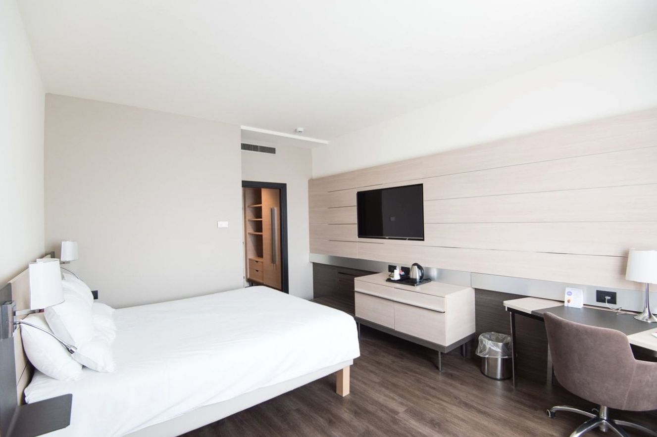 Bright standard room with pale oak and soft linen
